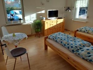 um quarto com 2 camas, uma mesa e uma televisão em Fewo Rosi em Brotterode