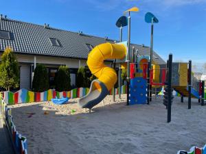 a playground with a yellow slide in the sand at Amelia Resort in Sianozety