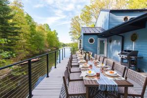 a deck with wooden tables and chairs on a house at King Suites, Lakefront, Hot Tub, Watercraft in Harpers Ferry