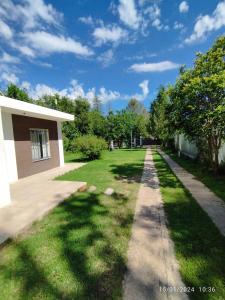 un patio de césped con un edificio y un árbol en Alojamiento Cuchi Corral en San Luis