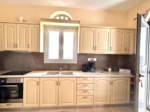 a kitchen with white cabinets and a sink at Aegean View House in Agios Ioannis