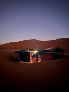 eine Person, die in einem Zelt in der Wüste sitzt in der Unterkunft Gambe Camp in Adrouine