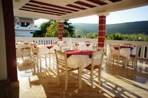 un restaurante con mesas blancas y sillas en un balcón en Hotel Alexandros en Ammoudia