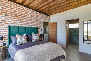 Schlafzimmer mit Ziegelwand und Bett in der Unterkunft Steenbok farm cottages Kingfisher Cottage in Wolseley