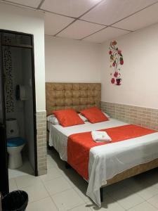 1 dormitorio con 1 cama grande con almohadas rojas en Hotel Mi Casita Pereira, en Pereira