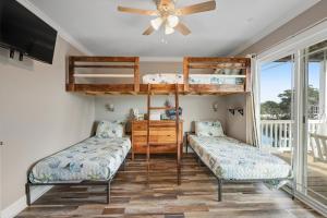 two bunk beds in a room with a ceiling fan at Bird's Nest in Holden Beach