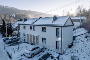 una casa bianca con un'auto parcheggiata nella neve di Apartament Kasztanowy blisko centrum - Dream Apart a Szczyrk