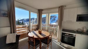 a kitchen with a table and chairs and a large window at T3 STANDING CENTRE STATION VALBERG in Valberg