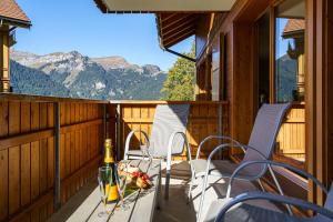 einen Balkon mit Stühlen und einem Tisch mit einer Flasche Wein in der Unterkunft Chalet Aquila 5 in Wengen