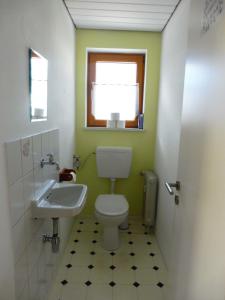 ein Bad mit einem WC, einem Waschbecken und einem Fenster in der Unterkunft Bobis Ferienwohnung in Wildpoldsried