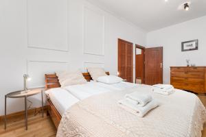 2 Betten in einem weißen Schlafzimmer mit Handtüchern darauf in der Unterkunft Tagore 3 by Homeprime in Warschau