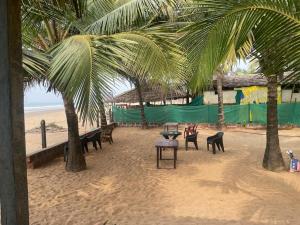 una playa con palmeras, mesas y sillas en Nisarga Homestay, en Gokarna