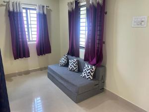 sala de estar con cortinas moradas y sofá con almohadas en Nisarga Homestay, en Gokarna