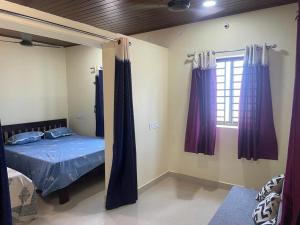 1 dormitorio con 1 cama y una ventana con cortinas moradas en Nisarga Homestay, en Gokarna