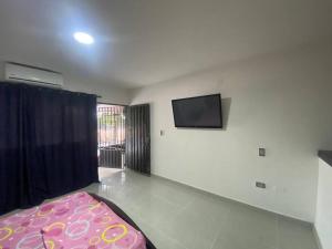 sala de estar con cama y TV de pantalla plana en Comfortable apartment very close to the airport, en Cúcuta