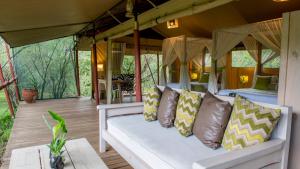 eine Veranda eines Safarizelts mit einer Couch und Kissen in der Unterkunft Soroi Private Wing in Masai Mara