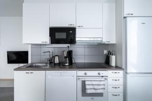 a white kitchen with a sink and a microwave at Lumiapartment1 in Rovaniemi