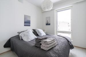 een slaapkamer met een bed met dekens en kussens bij Lumiapartment1 in Rovaniemi