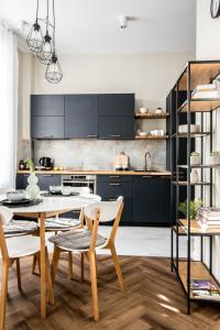a kitchen with black cabinets and a table and chairs at Designerski apartament w centrum Kazimierza in Krakow