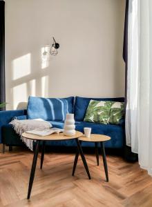 a living room with a blue couch and two tables at Designerski apartament w centrum Kazimierza in Krakow