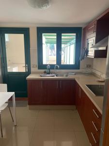 a kitchen with wooden cabinets and a sink and two windows at Apartamento en Plaza del Charco in Puerto de la Cruz