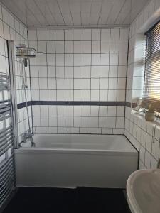 a white bathroom with a tub and a sink at Double bedroom located close to Manchester Airport in Wythenshawe +7 photos