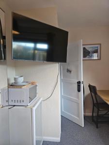 a room with a microwave and a tv on a wall at Double bedroom located close to Manchester Airport in Wythenshawe