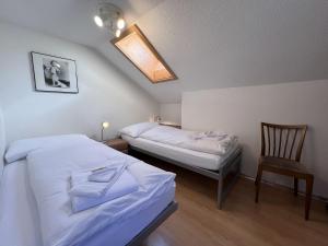 um pequeno quarto com 2 camas e uma cadeira em Chalet Tilia Penthouse em Wengen