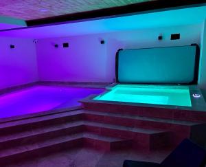a room with a tub with purple and blue lights at Jolie cabane avec jacuzzi pour les amoureux de la nature in Tullins