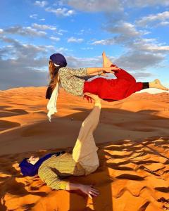El GoueraにあるChegaga Regency Campの砂漠の砂に横たわっている二人