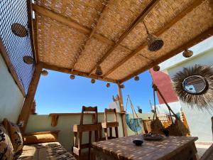 a patio with a wooden table and a straw roof at Palmsurfexpo in Imsouane
