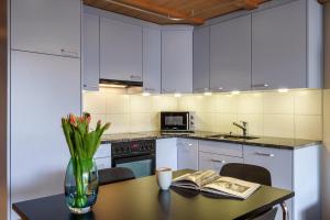a kitchen with white cabinets and a table with a vase of flowers at Kinohaus 7 in Wengen +23 photos