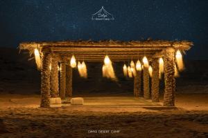 a wooden arch with lights in the desert at night at Dihya desert camp in Merzouga