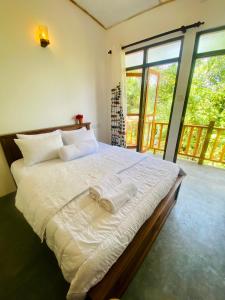 um quarto com uma cama grande e lençóis brancos em Jungle Beach Inn em Unawatuna