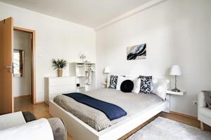 a white bedroom with a bed and a couch at Panna Marina Apartment by NW in Budapest