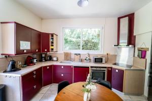 a kitchen with purple cabinets and a wooden table at Appart Face Loire Blois Terrasse Parking Jardin Jacuzzi Parking Vélos in Blois