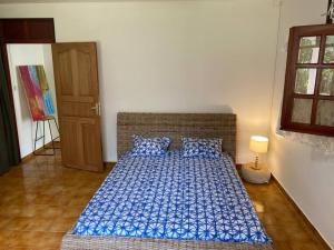 Schlafzimmer mit einem Bett mit blauer Bettwäsche und einer Lampe in der Unterkunft Zayann Zen in Gourbeyre