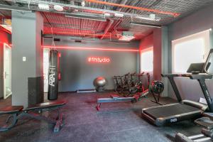 a gym with cardio equipment in a room with red walls at Micampus Getafe II Student Residence in Getafe