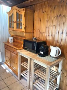 eine Küche mit Holzwänden und einem Tisch mit einer Mikrowelle in der Unterkunft Cosy mountain apartment 5min walk from Gondola in Fiesch