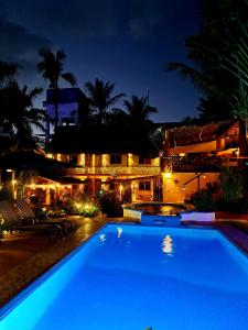a swimming pool in front of a building at night at Hotelito Swiss Oasis -Solo Adultos - Adults only in Puerto Escondido