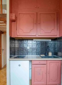 a kitchen with red cabinets and a sink at Appartement climatisé en plein centre avec balcon in Saint-Jean-Cap-Ferrat