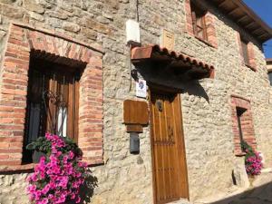 un edificio de ladrillo con una puerta y flores en él en Genciana, Casa Rural con encanto en La Montaña Leonesa, 