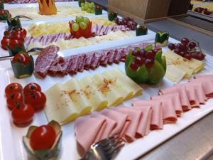 a table with many different types of cheese and tomatoes at Saalbach Suites by ALPS RESORTS in Saalbach Hinterglemm