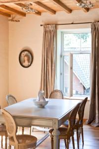 una sala da pranzo con tavolo, sedie e finestra di Lozerkasteel a Kruishoutem