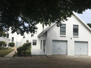 a white house with two garage doors at Summerhill Self-Catering Accommodation St Francis Bay in St Francis Bay