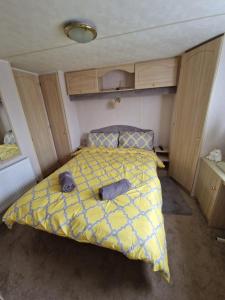 a bedroom with a bed with a yellow comforter at Caravan F8 Aberystwyth Holiday Village in Aberystwyth