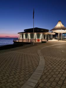 a building on the beach with the ocean in the background at Hilltop Hideaway 2 Bed Caravan with Panoramic Town Scenery in Aberystwyth Holiday Village F8 in Aberystwyth