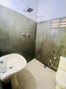 ein Badezimmer mit Waschbecken und Toilette in der Unterkunft Jungle Beach Inn in Unawatuna