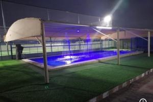 an empty tennis court at night with a pool at Rahalt alsharq in Ibrā