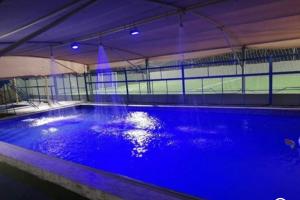 a large swimming pool with blue water in a building at Rahalt alsharq in Ibrā